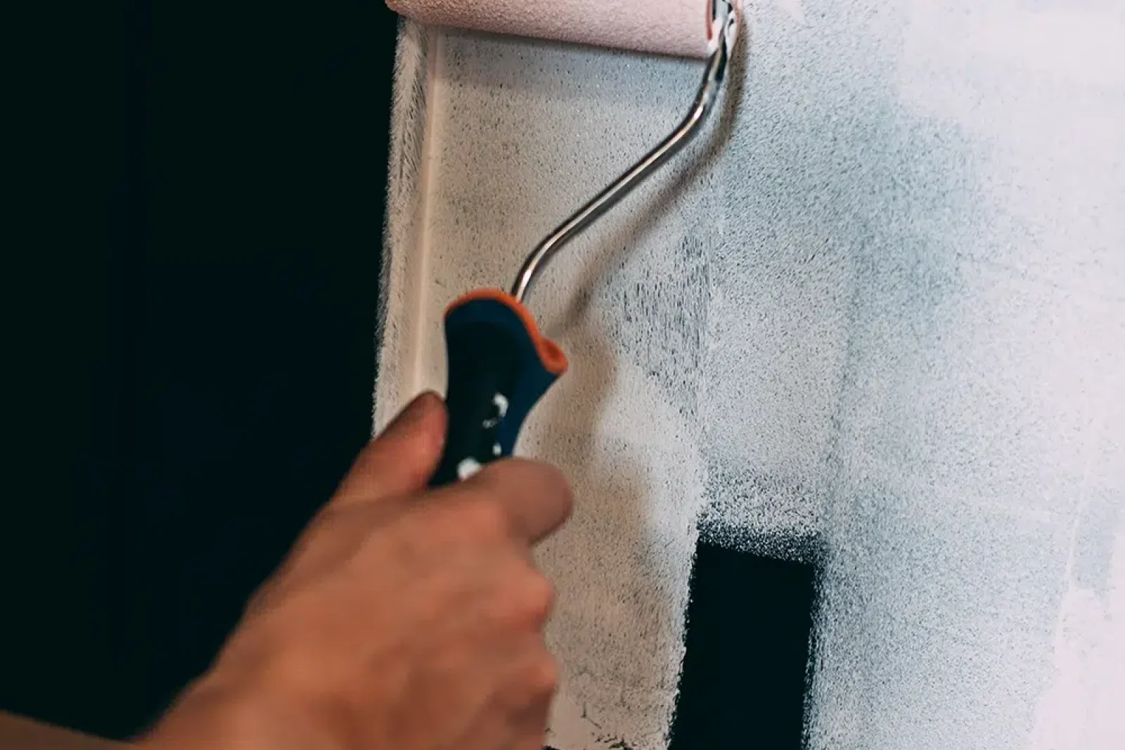 A Qualified Painter using a small painter roller to cut in a corner of wall on the Central Coast, NSW